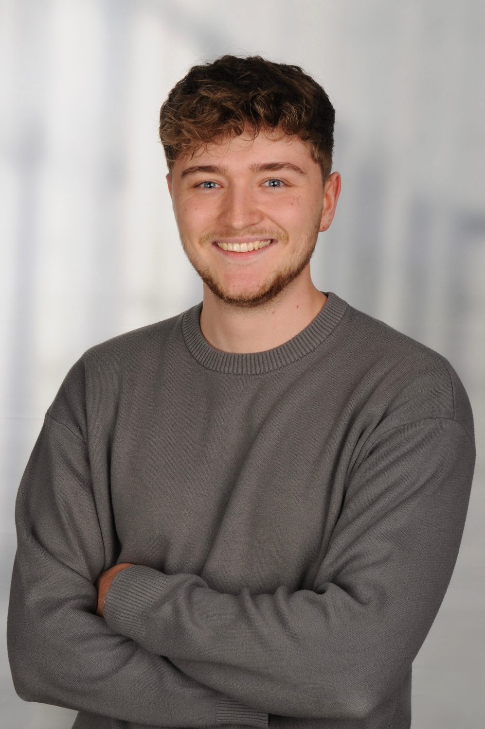 Leon Saynisch, Gründer von TrustLap IT, im grauen Pullover mit verschränkten Armen